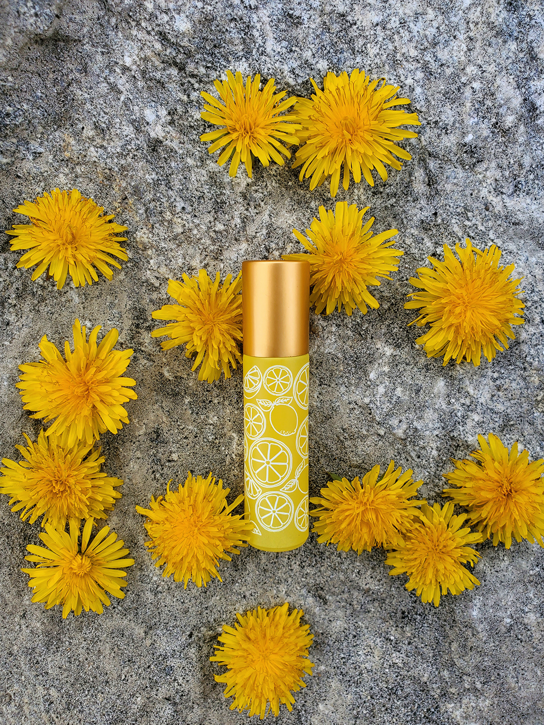 lemon roller bottle with dandelions on wood whimsy + wellness
